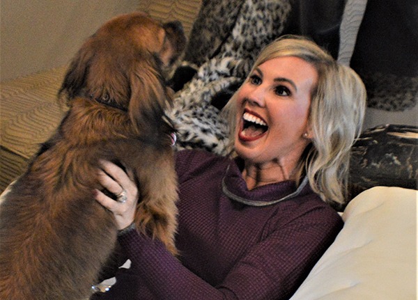 woman holding dog and exclaiming in joy